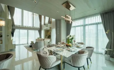 Luxurious open-plan living and dining area with elegant decor and floor-to-ceiling windows.