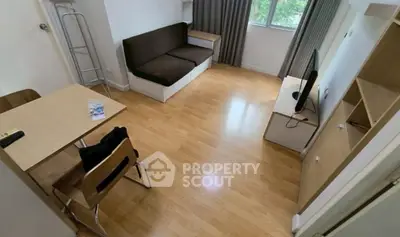 Cozy living room with wooden flooring, modern furniture, and natural light from window.