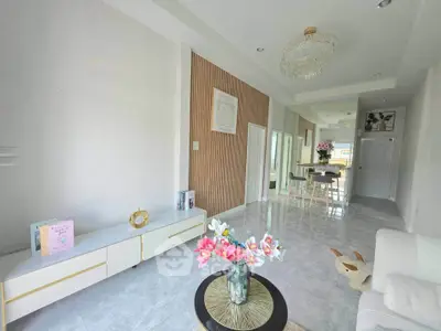Elegant living room with modern decor and chandelier, featuring a cozy seating area and stylish dining space.