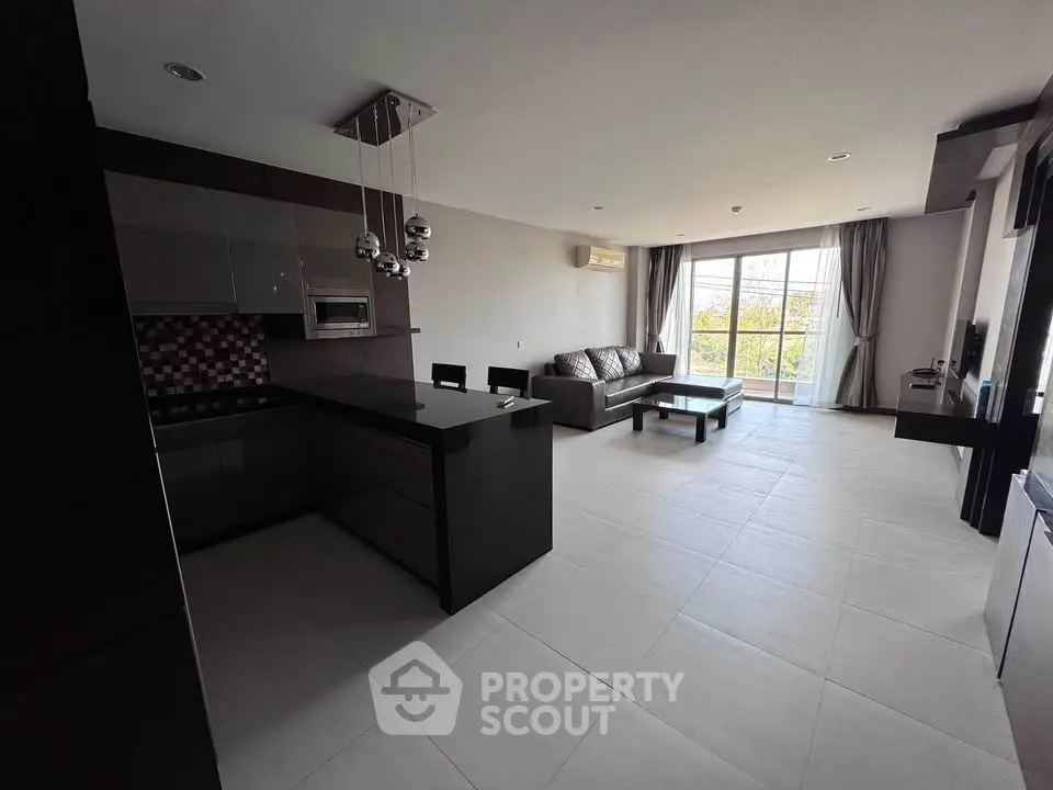 Spacious modern living room with open kitchen and large windows for natural light.