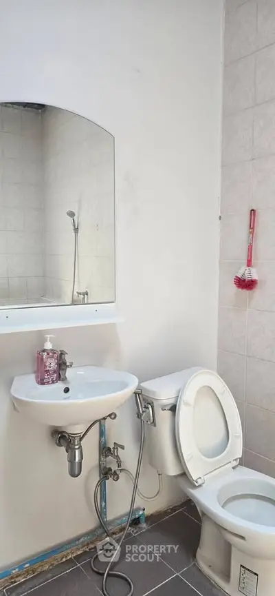 Compact bathroom with sink, toilet, and wall-mounted mirror in a minimalist design.