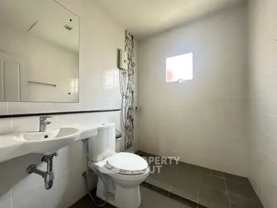 Modern bathroom with sleek design and natural light, featuring a shower area and contemporary fixtures.