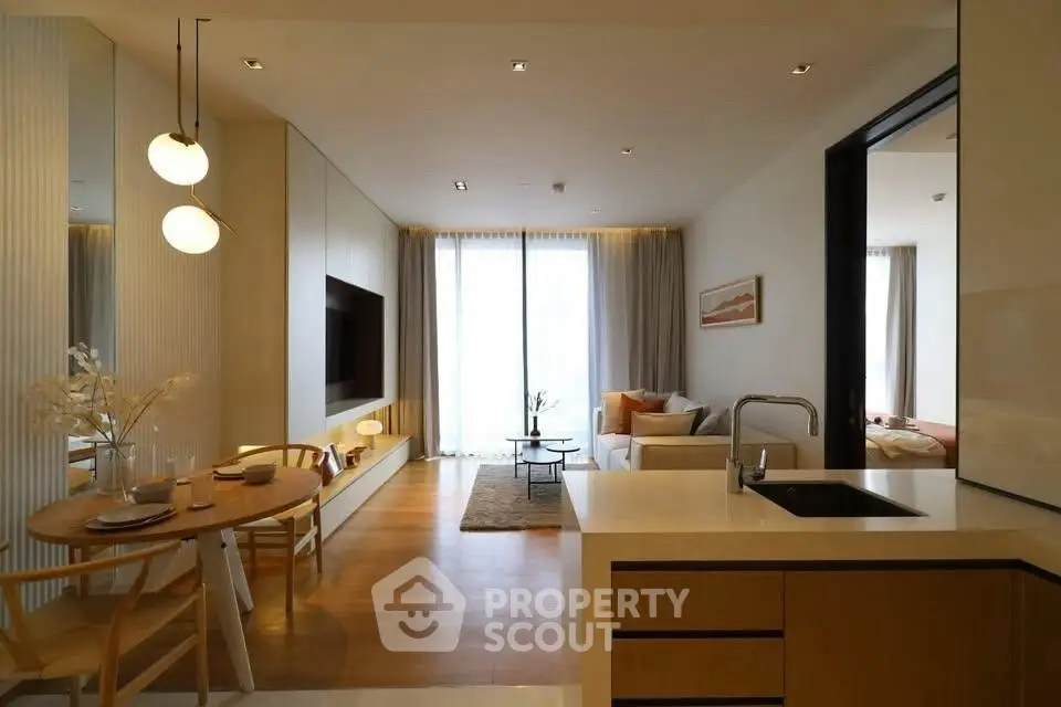 Modern open-plan living room with stylish kitchen and dining area, featuring elegant lighting and cozy decor.
