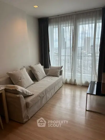 Bright living room with cozy sofa and city view through large window.