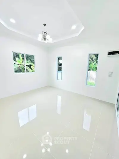 Bright and spacious empty room with glossy tiled floor and modern chandelier.