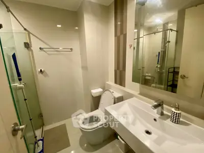 Modern bathroom with sleek fixtures and glass shower enclosure in a contemporary apartment.