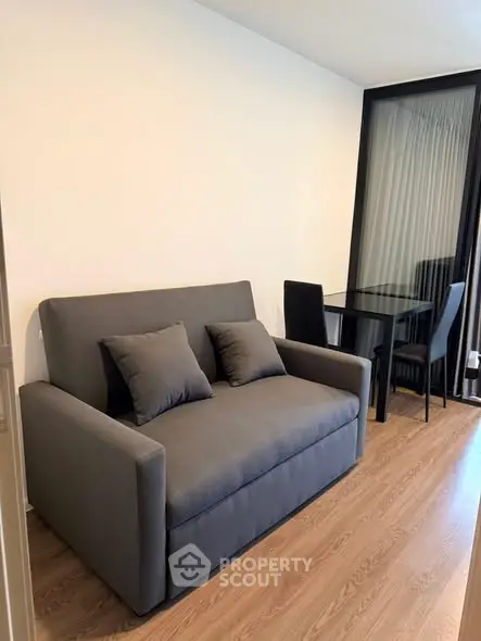 Modern living room with sleek gray sofa and glass dining table, perfect for urban living.