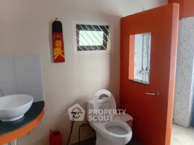Modern bathroom with unique orange accents and stylish fixtures.