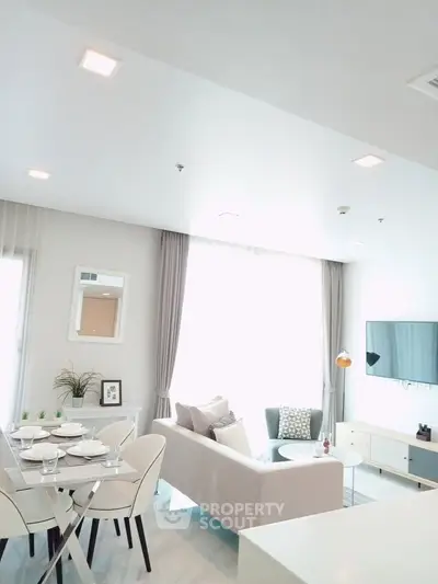 Modern living room with elegant decor and natural light, featuring a cozy seating area and stylish dining setup.