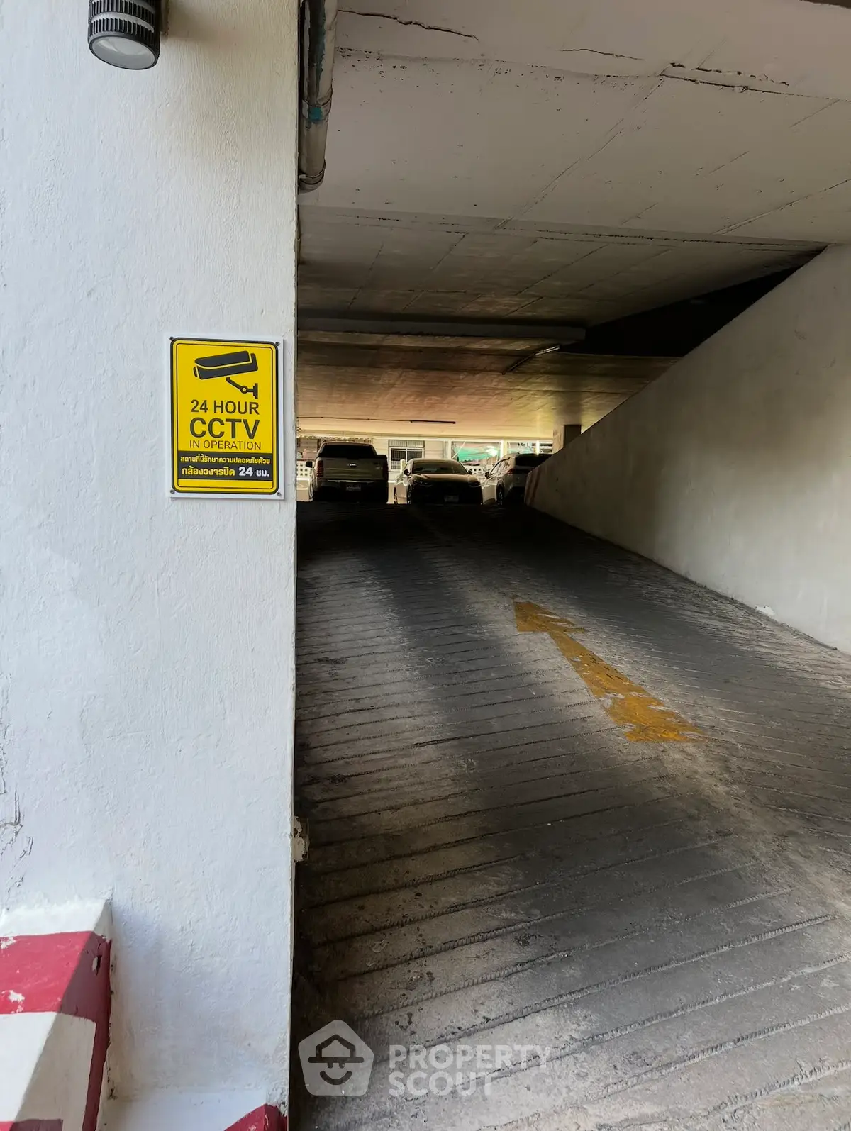 Secure parking garage with 24-hour CCTV surveillance, featuring a ramp and multiple parking spaces.