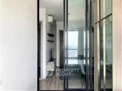 Modern apartment with glass sliding doors and city view, featuring sleek interior design and natural light.