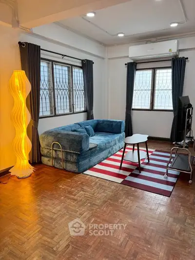 Cozy living room with modern sofa, stylish lamp, and striped rug in a well-lit space.