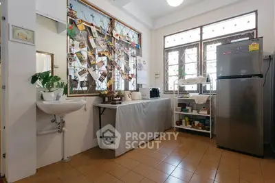 Charming kitchen with tiled floor, stainless steel fridge, and ample natural light.