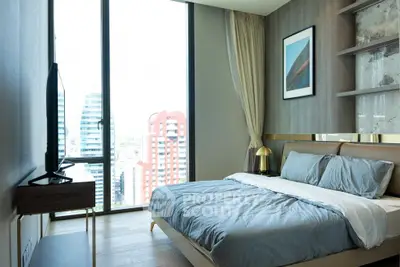 Modern bedroom with large window offering stunning city views, stylish decor, and cozy bedding.