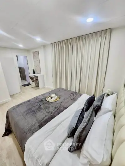 Luxurious bedroom with elegant decor and cozy ambiance, featuring plush bedding and stylish curtains.