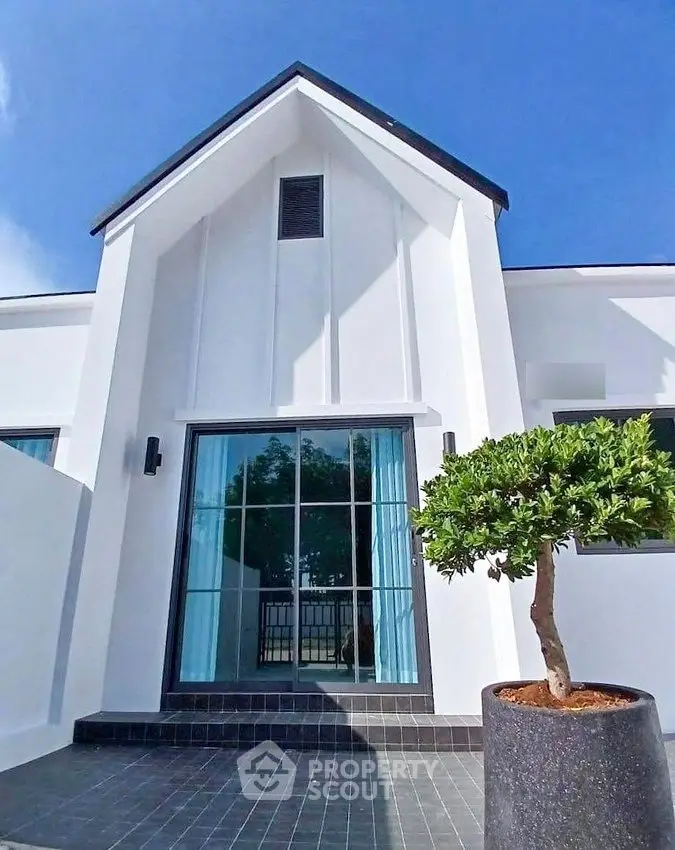 Modern white house exterior with sleek design and potted tree, showcasing contemporary architecture.