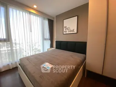 Modern bedroom with large window and stylish decor in a high-rise apartment.