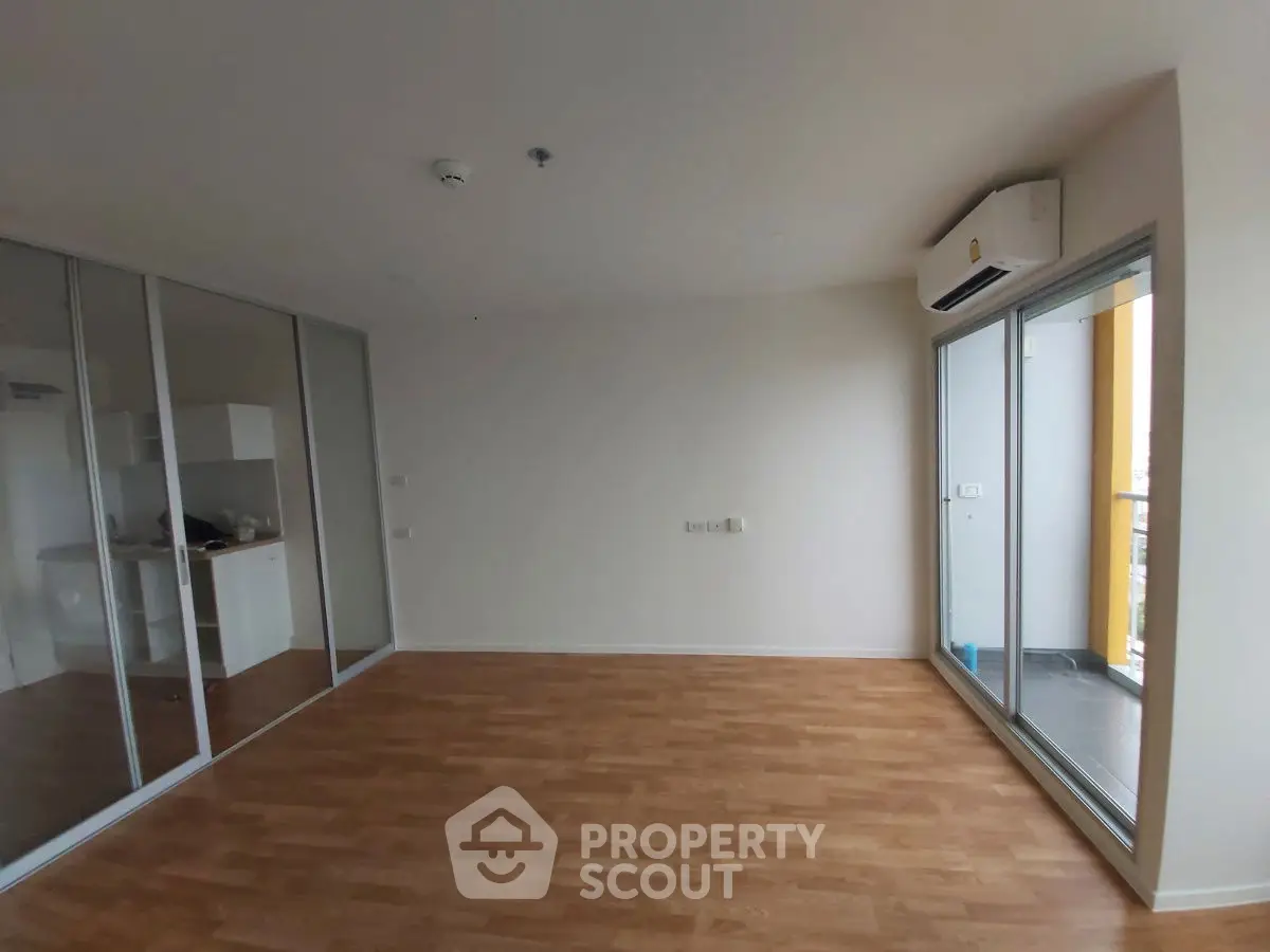 Spacious modern living room with wooden flooring and glass sliding doors to balcony.
