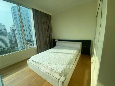Bright bedroom with large window offering stunning city views in modern apartment.