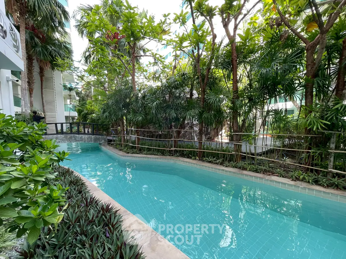 Luxurious outdoor pool surrounded by lush greenery in a modern residential complex.