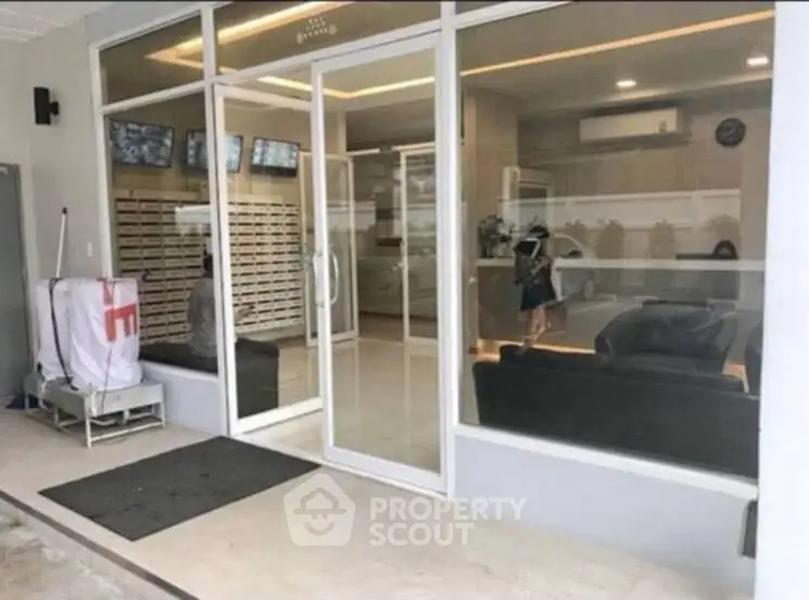 Modern building entrance with glass doors and sleek interior design, showcasing a welcoming lobby area.