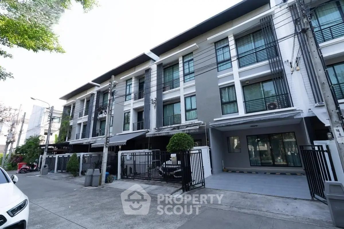 Modern townhouse exterior with sleek design and gated entrance in urban setting.