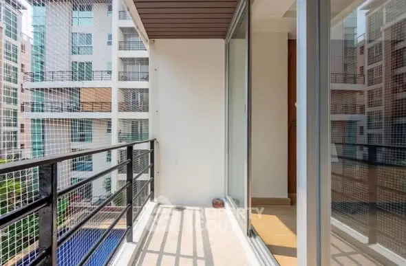 Spacious balcony with modern railing and glass doors in urban apartment complex.