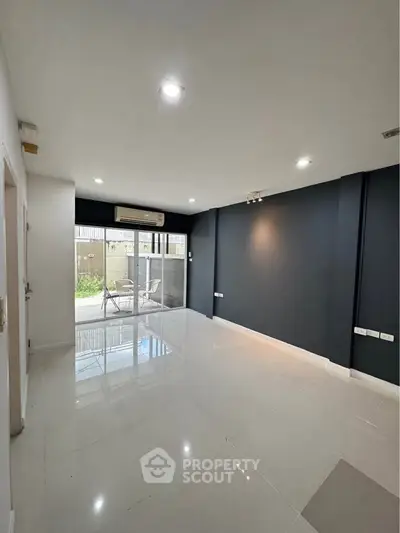 Spacious modern living room with sleek design and large windows opening to a patio.
