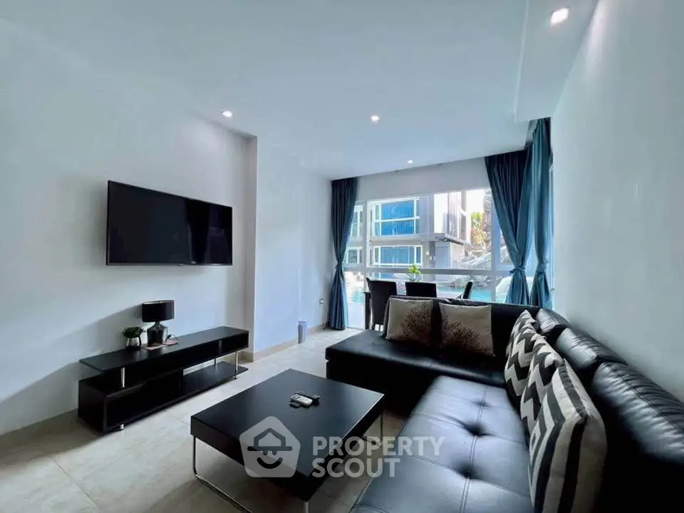 Modern living room with sleek black furniture and large window offering a stunning view of the cityscape.