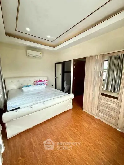 Spacious bedroom with elegant wooden flooring and modern furnishings in a luxurious apartment.