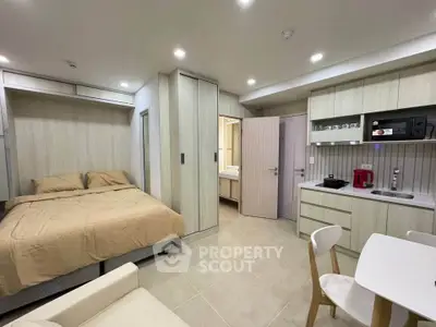 Modern studio apartment with cozy bed, compact kitchen, and dining area.