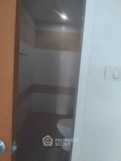 Compact bathroom with tiled walls and a toilet, ideal for small spaces.