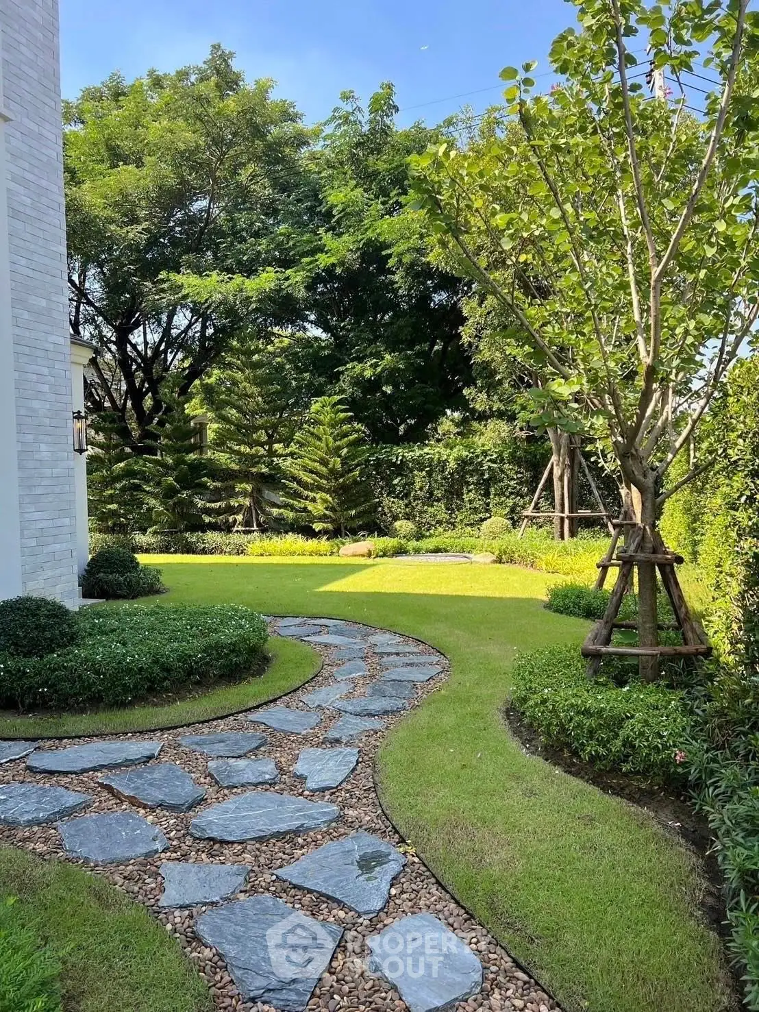 Charming garden with stone pathway and lush greenery in a serene residential setting.