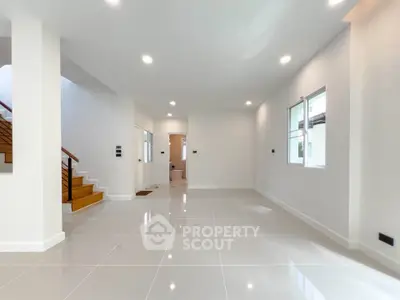 Spacious modern living room with glossy tiled floors and ample natural light.