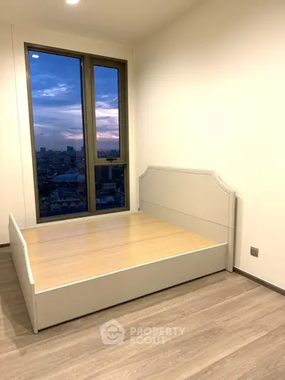 Modern bedroom with large window offering stunning city view at sunset