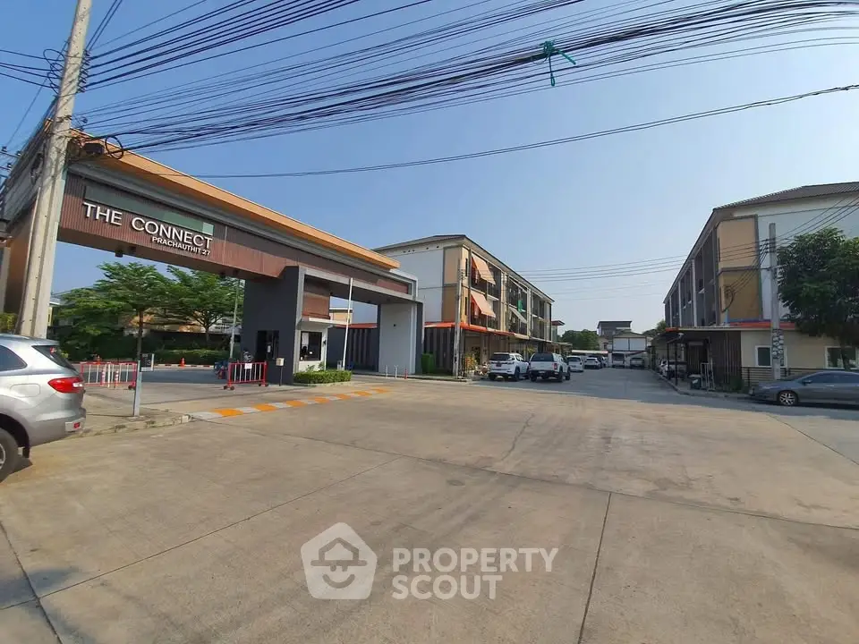 Modern residential complex entrance with spacious parking and contemporary architecture.