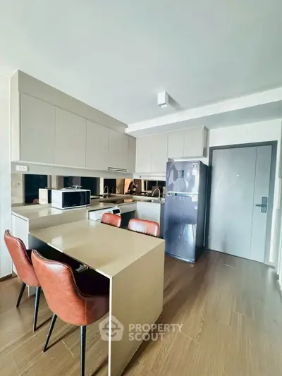 Modern kitchen with sleek cabinets and dining area in contemporary apartment.