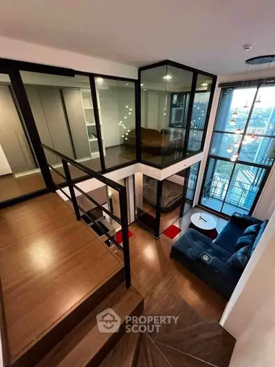 Modern duplex apartment with glass walls and stunning city view, featuring a stylish living area and elegant staircase.