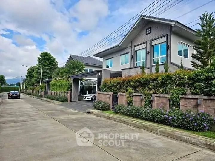 Modern two-story house with lush garden and driveway in suburban neighborhood.