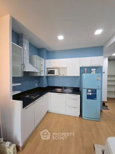 Modern kitchen with blue accents, sleek cabinetry, and appliances in a stylish apartment.