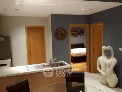 Modern open-plan kitchen and dining area with artistic decor and bedroom view.