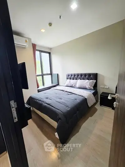 Modern bedroom with large window and stylish decor in a cozy apartment.