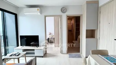 Modern apartment interior with open living room, TV, and view of bedroom and bathroom.
