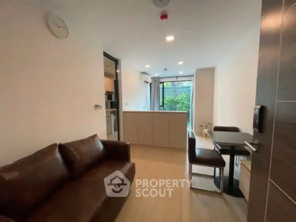 Modern living room with brown leather sofa and dining area in open layout.
