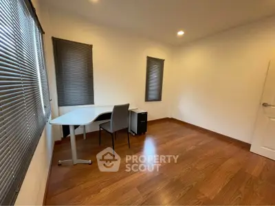 Spacious study room with modern desk and chair, featuring elegant wooden flooring and ample natural light.
