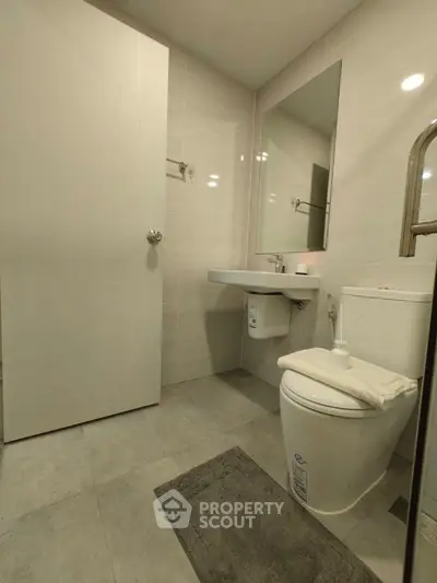 Modern bathroom with sleek fixtures and minimalist design, featuring a wall-mounted sink and large mirror.