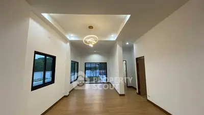 Spacious modern living room with elegant lighting and large windows overlooking greenery.