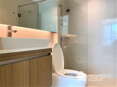 Sleek modern bathroom with wall-mounted sink, mirrored cabinet, and glass-enclosed shower, showcasing a minimalist design.