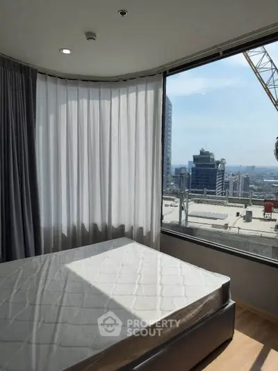 Modern bedroom with large window offering stunning city view and natural light.