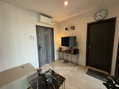 Modern living room with stylish decor and wall-mounted TV, featuring a sleek air conditioning unit and elegant clock.